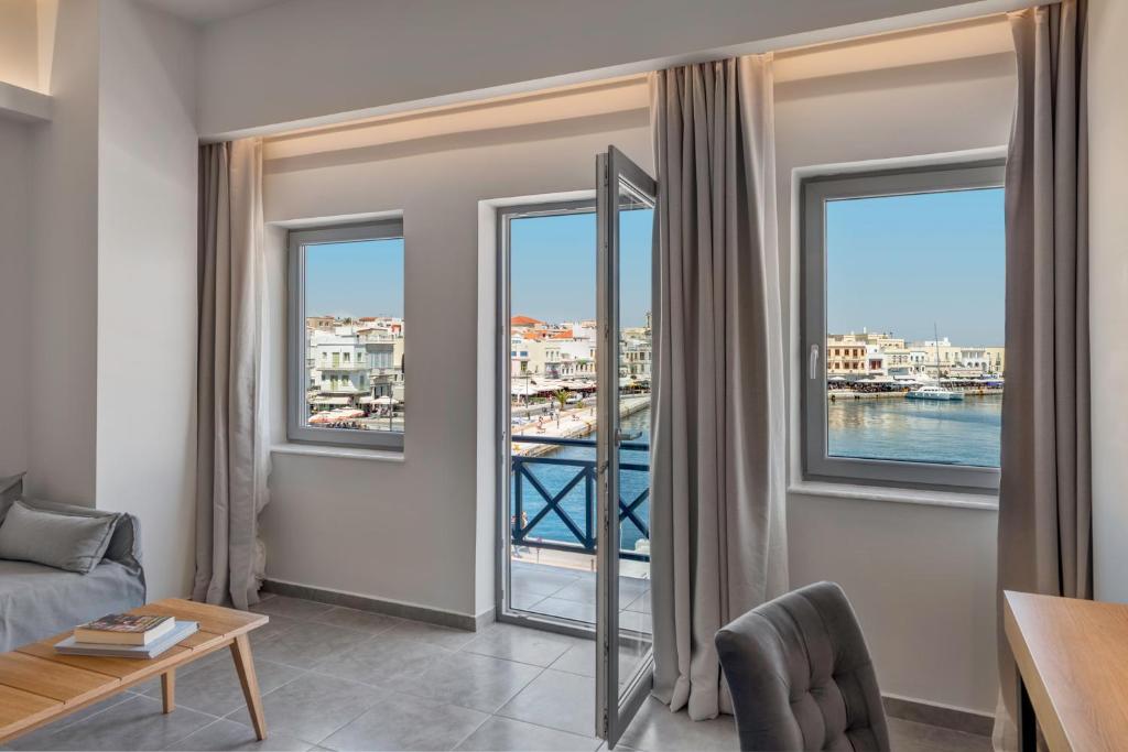 a living room with windows with a view of the water at Naves Suites in Ermoupoli