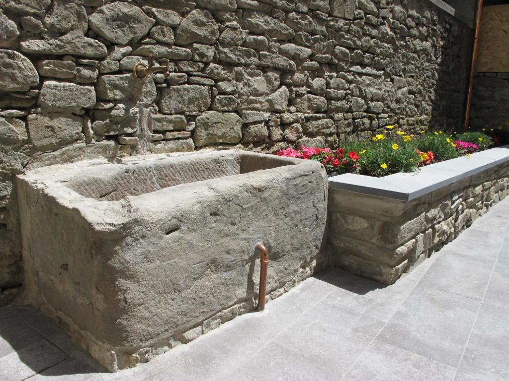 ボルゴ・サン・ロレンツォにあるPippo B&Bの石壁の前に花を咲かせる石造りのバスタブ