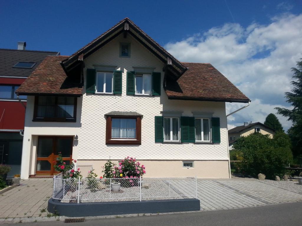 una casa blanca con persianas verdes y flores delante en Ferienhaus und Ferienappartements Brunner en Höchst