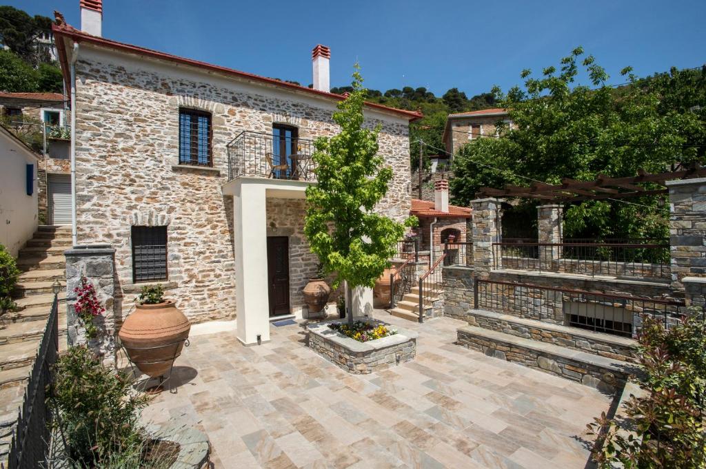 una casa de piedra con un patio con un árbol en Thalia Traditional Guest House, en Promírion