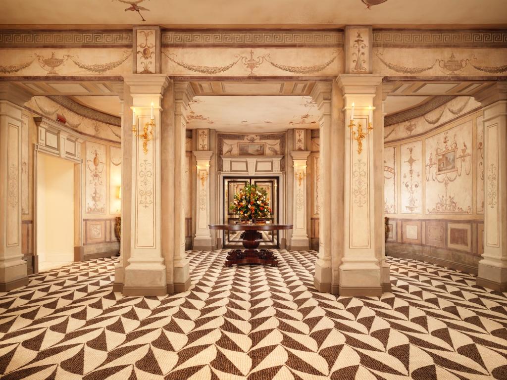 a hallway with columns and a table with a plant at Hotel Eden - Dorchester Collection in Rome