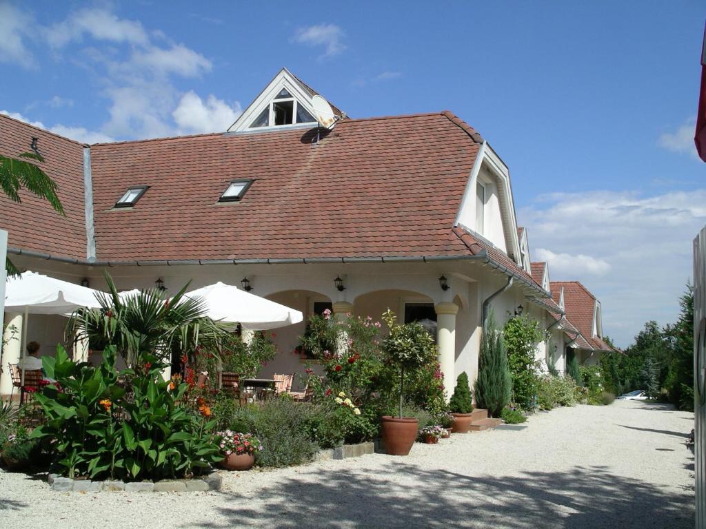 un edificio con techo rojo y algunas plantas en Albergo Giardino en Balatongyörök