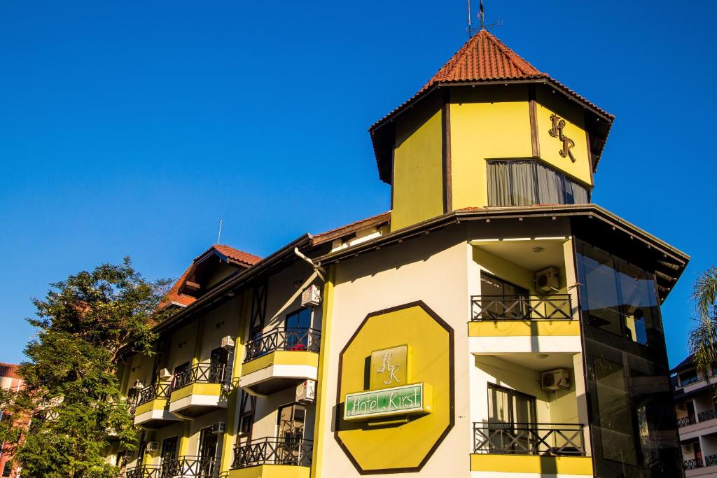 un edificio amarillo y blanco con una torre de reloj en Hotel Kirst en Piratuba