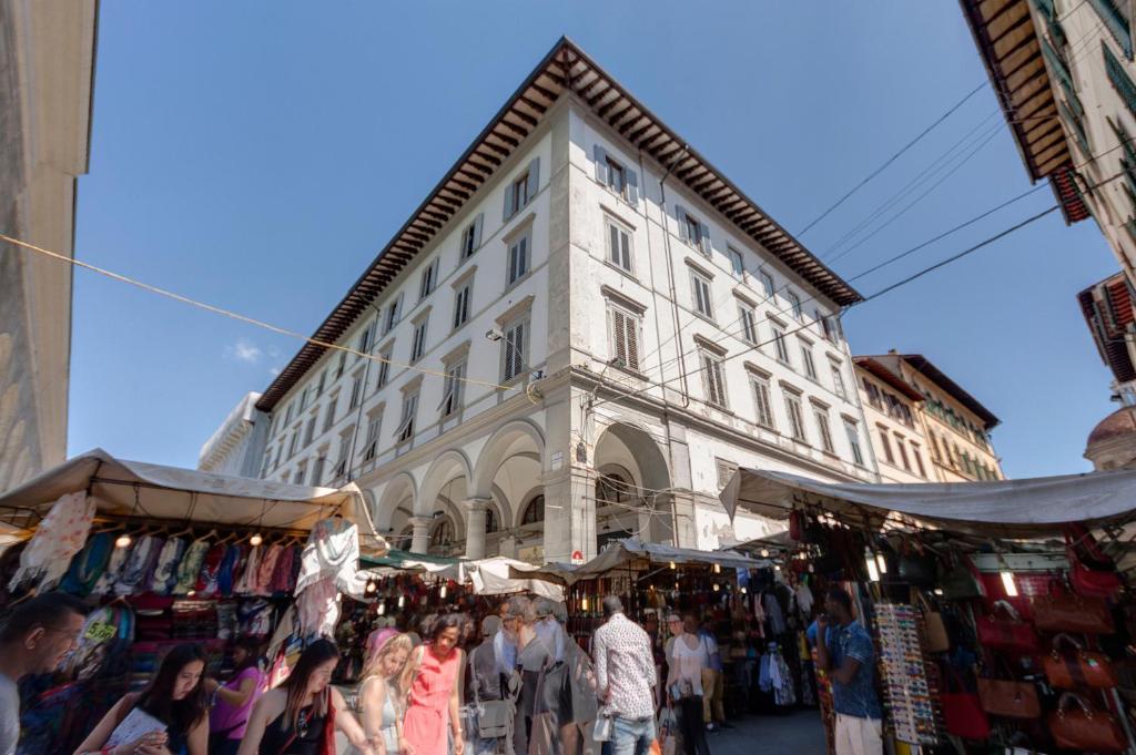 Eine Menschenmenge, die vor einem Gebäude auf einem Markt herumläuft in der Unterkunft Cappelle Medici in Florenz