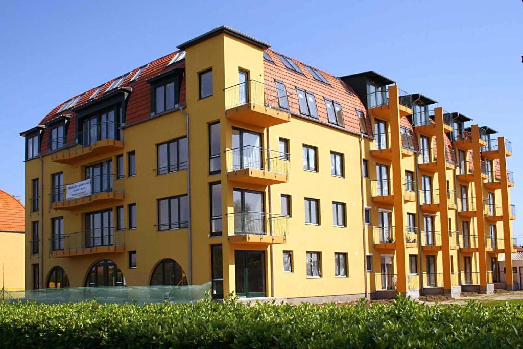 un gran edificio amarillo con balcones. en Udvarház Apartman, en Mórahalom