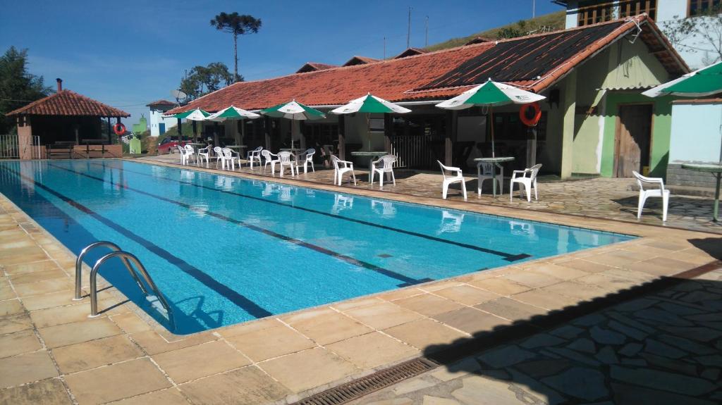 a large swimming pool with chairs and umbrellas at Hotel Fazenda Selva do Mato Limpo in Rio Prêto