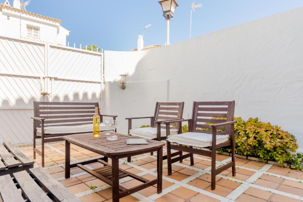 a patio with three chairs and a wooden table at Duplex El Manantial in El Puerto de Santa María