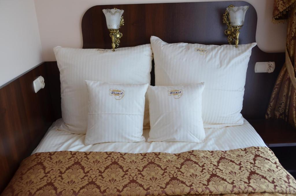 1 cama con almohadas blancas y cabecero en Dormed Medical SPA en Busko-Zdrój