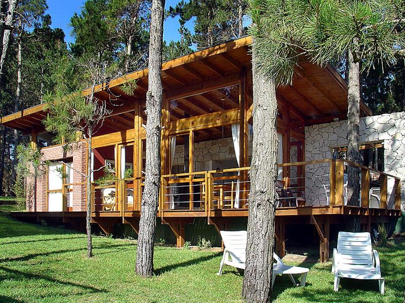 a house with two chairs in front of it at Cabañas San Dionisio in Mar de las Pampas