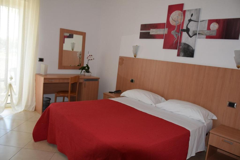 una camera da letto con un letto con una coperta rossa e uno specchio di Hotel Maggiore a Vieste
