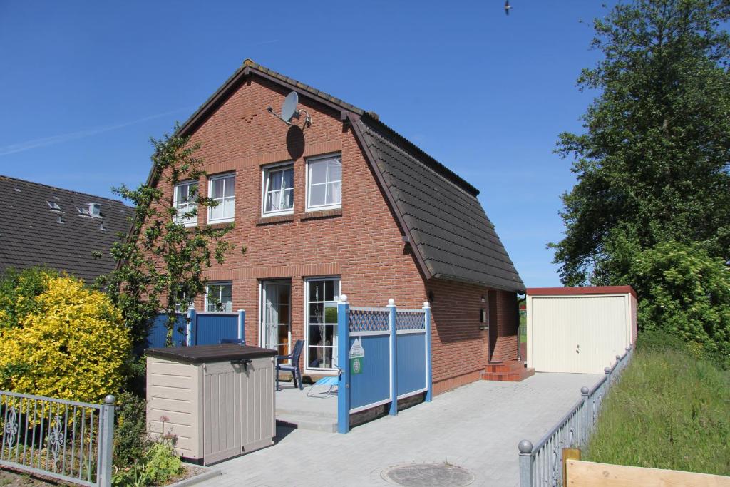a brick house with a fence in front of it at Deichschaf in Dornumersiel
