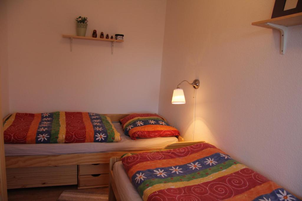 1 Schlafzimmer mit 2 Betten und bunten Decken in der Unterkunft Kleine Seenadel in Dornumersiel