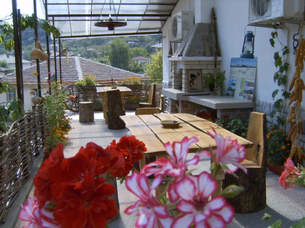 Georgievi Guest House في كالوفر: طاولة مع الزهور الحمراء والوردية على الفناء