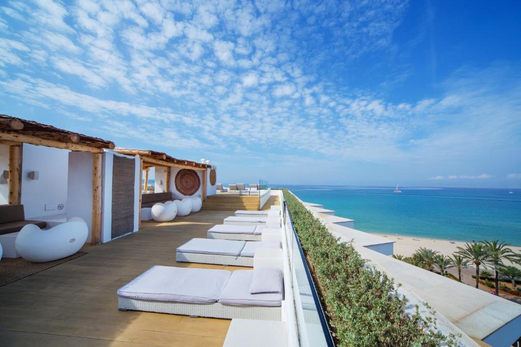 uma fila de espreguiçadeiras numa varanda com vista para a praia em HM Tropical em Playa de Palma