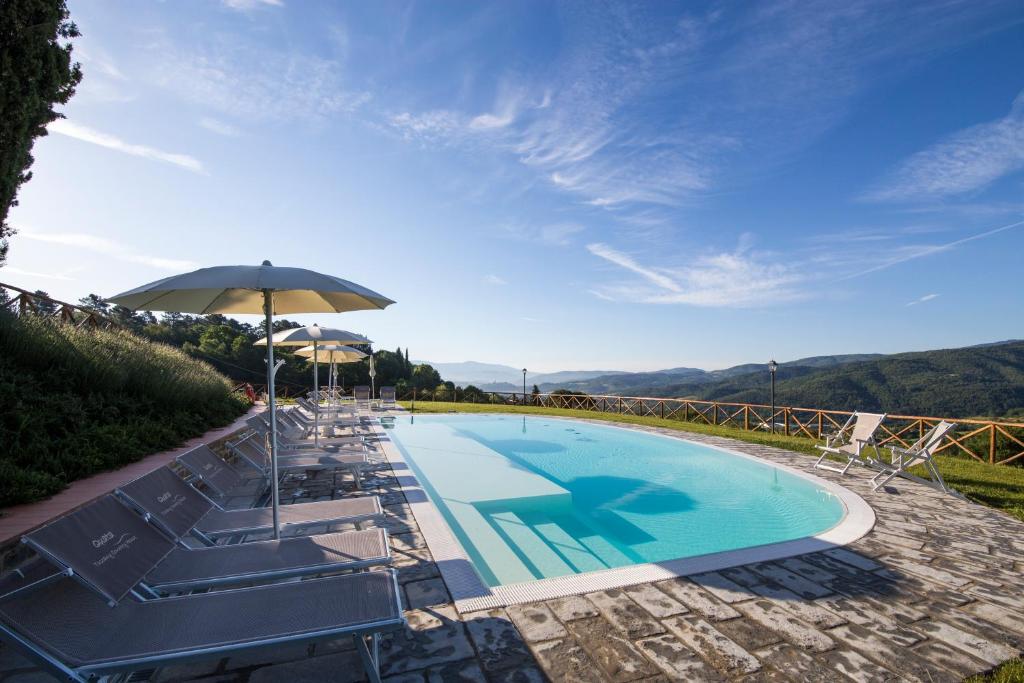 einen Pool mit Stühlen und einem Sonnenschirm in der Unterkunft Agriturismo Quata Country House in Borgo alla Collina
