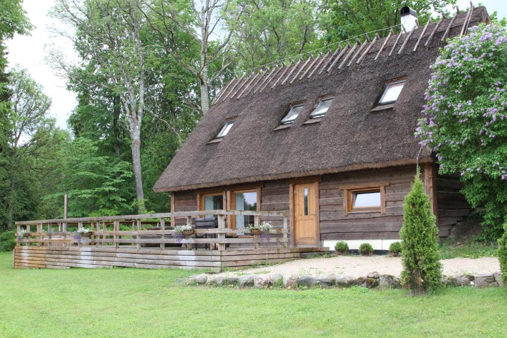 a wooden house with a gambrel roof and a fence at Tammeveski Holiday House in Kobruvere