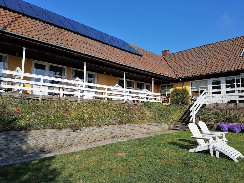 two white chairs sitting in the grass in front of a building at Hammerknuden in Allinge