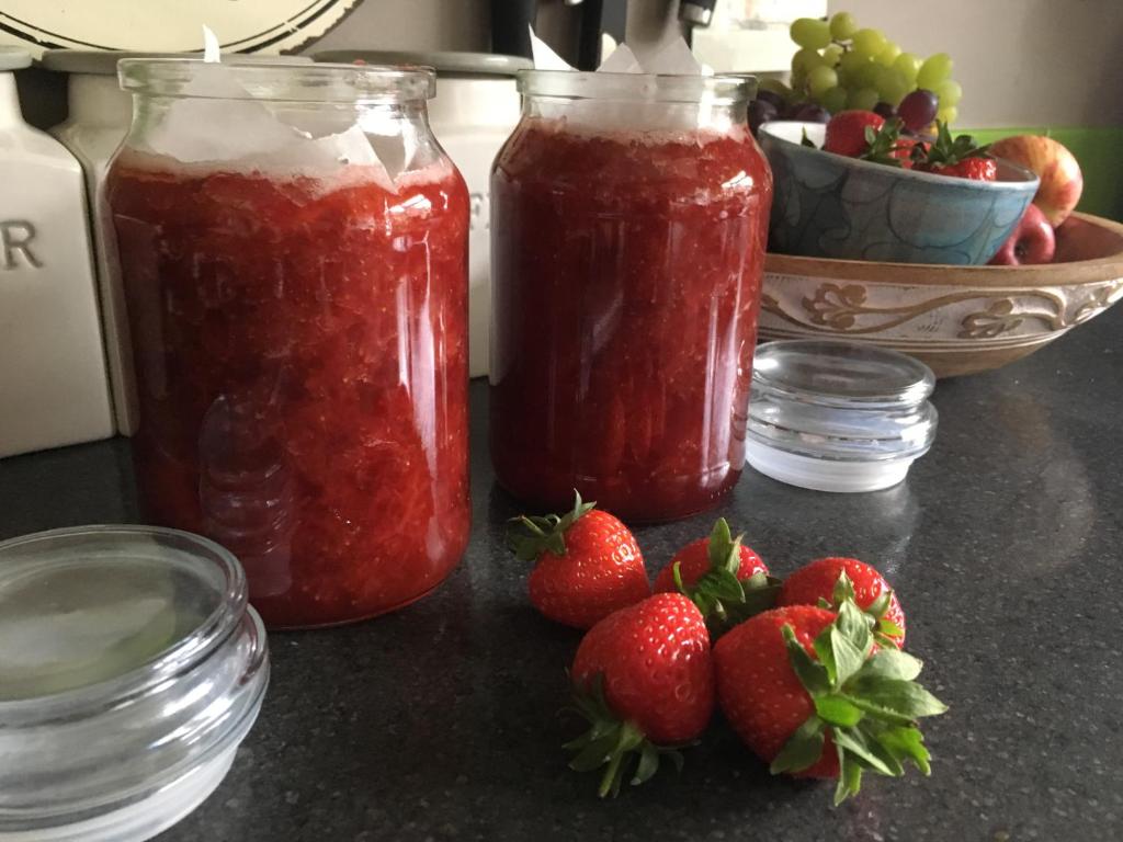 three jars of strawberry jam next to strawberries and a bowl of grapes at Alpine cottage in Crieff