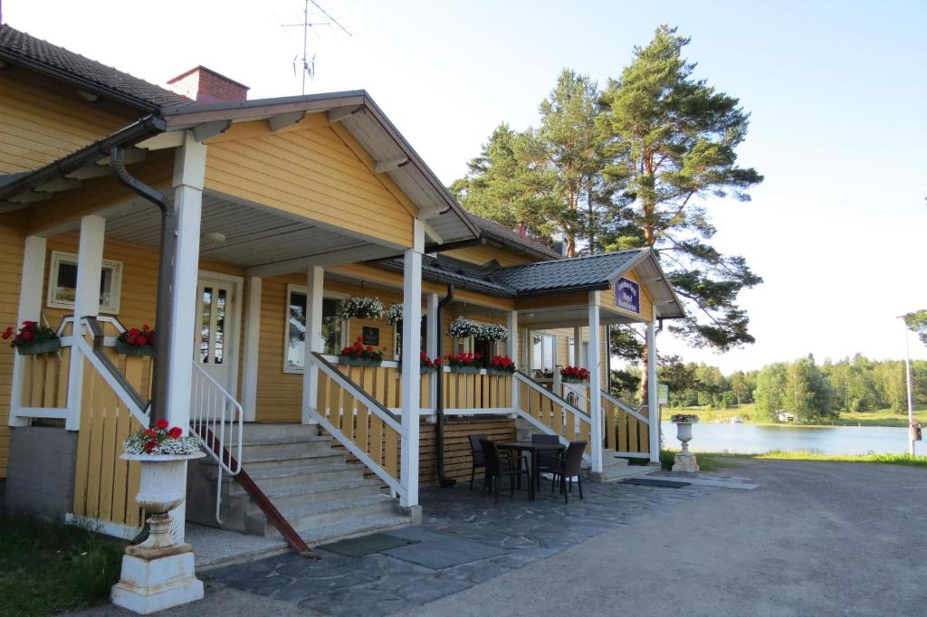 ein Haus mit einer Veranda mit einem Tisch und Stühlen in der Unterkunft Hotel Laatokan Portti in Parikkala