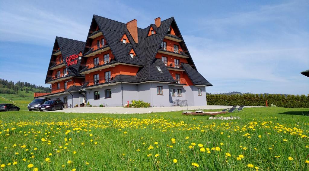 un grand bâtiment avec un toit dans un champ de fleurs dans l'établissement Czerwone Wierchy - sauna i jacuzzi wliczone w cenę pobytu!, à Białka Tatrzańska