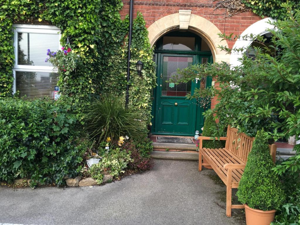 a wooden bench sitting in front of a green door at Oak Tree Guest House in Farnborough