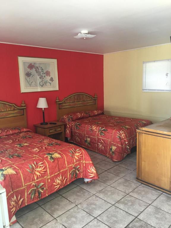 two beds in a room with red walls at Shelton Motel in Rio Grande