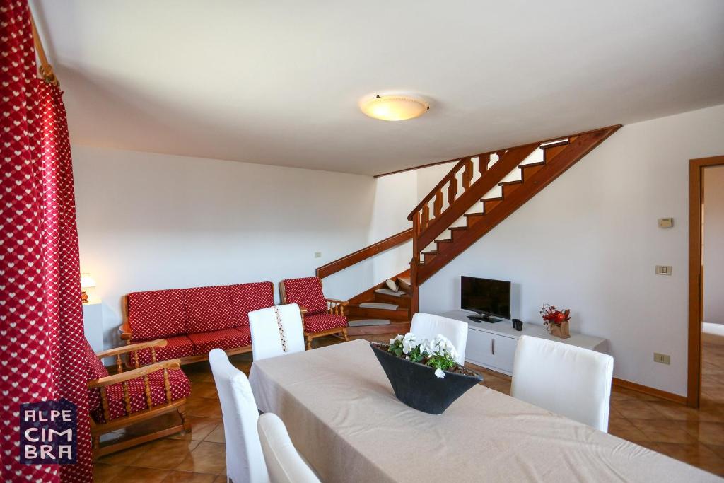 a living room with a table and chairs and a staircase at Chalet Laila in Folgaria