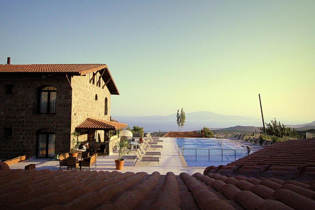 a building with a swimming pool next to a house at Assos Sunaba Kasri Hotel in Behramkale