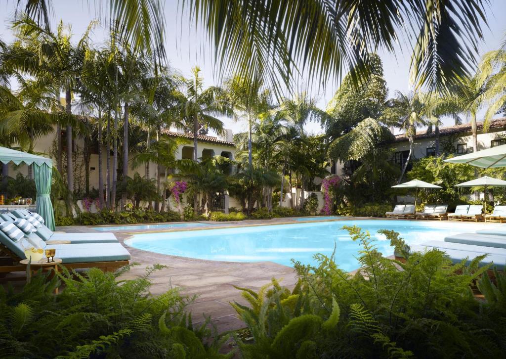 a large swimming pool with chairs and palm trees at Four Seasons Resort The Biltmore Santa Barbara in Santa Barbara