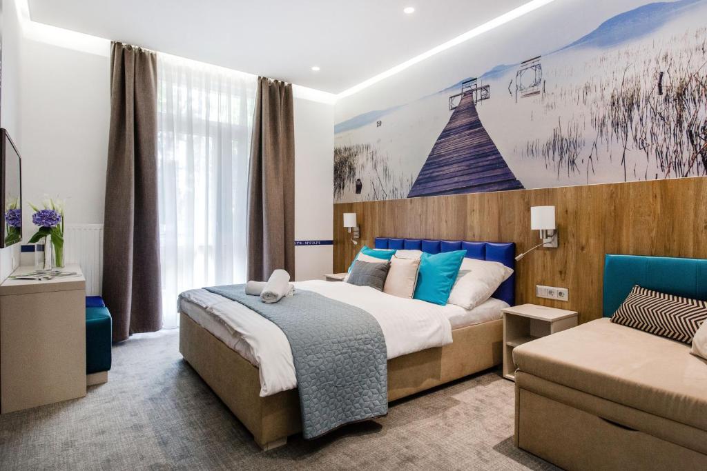 a bedroom with a large bed and a couch at Hotel Solero in Si&oacute;fok