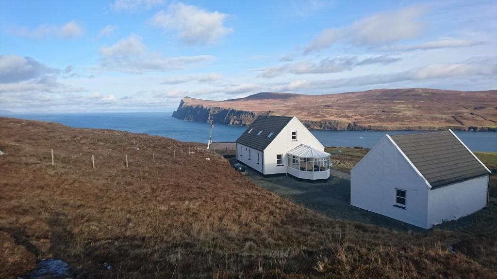 two white houses on a hill next to the ocean at Waterfall View in Milovaig