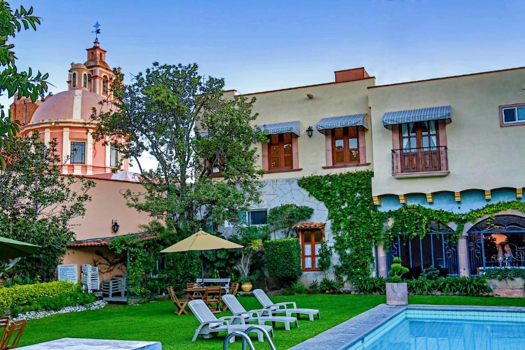 uma casa com piscina e cadeiras e um edifício em Hotel La Plaza de Tequisquiapan em Tequisquiapan