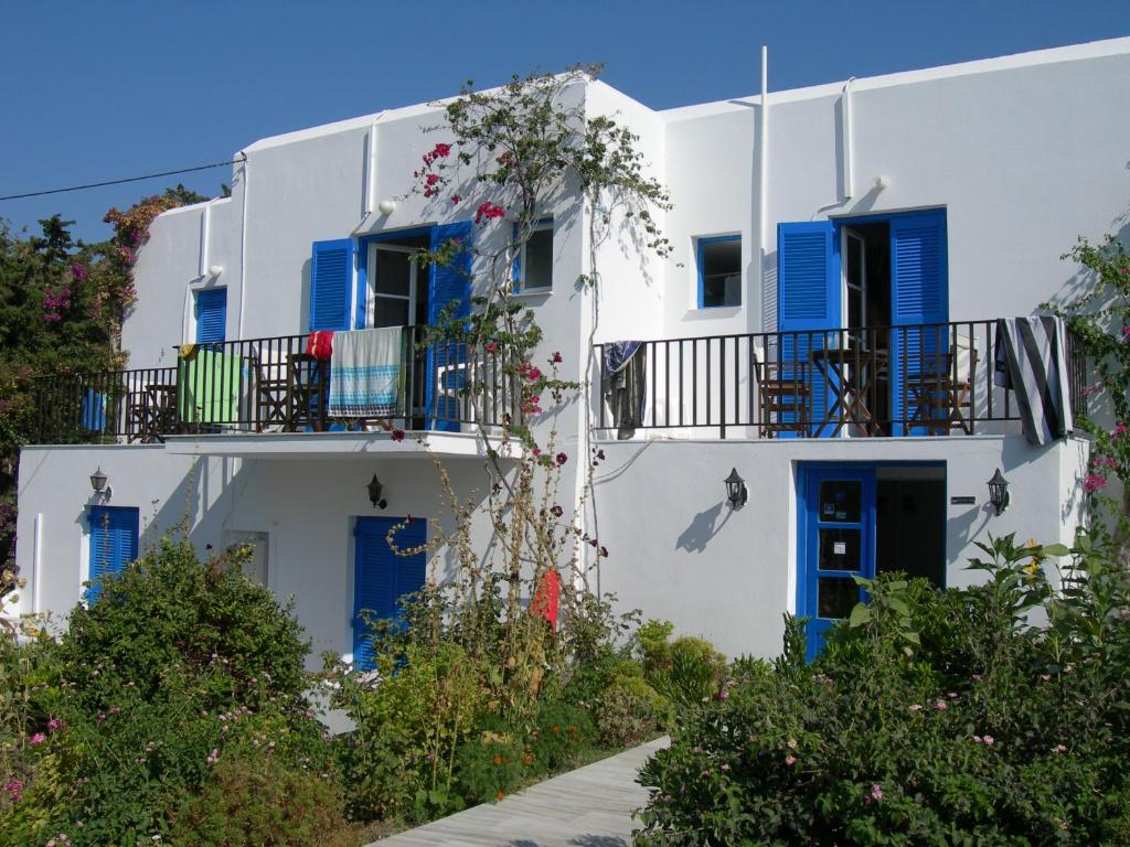 a white building with blue shutters and a balcony at Bizas Rooms & Studios in Parikia