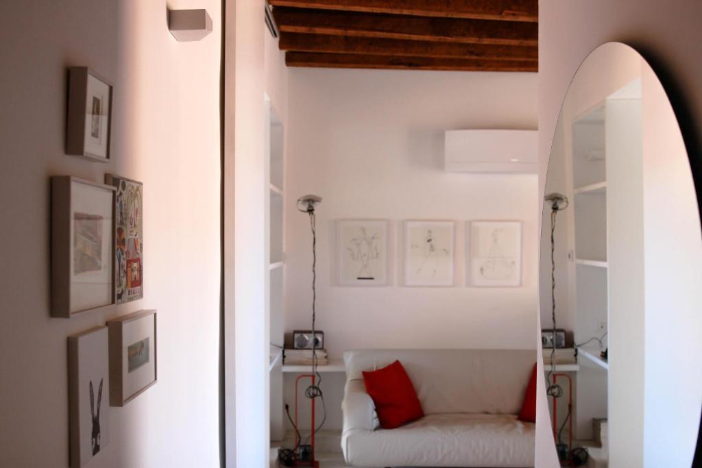ミラノにあるDesign apartment Porta Veneziaのリビングルーム(白いソファ、赤い枕付)