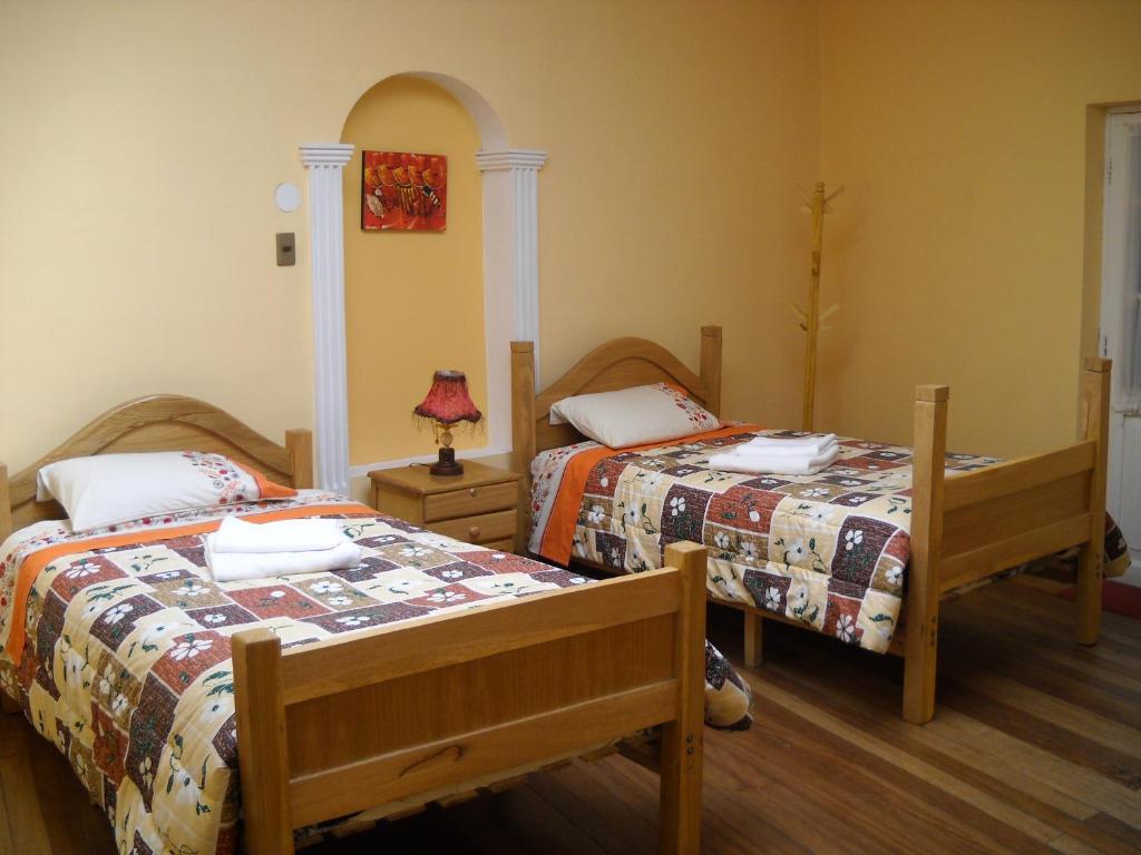 a bedroom with two beds and a lamp at Hostal Isidoros in La Paz
