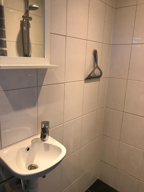 Un baño blanco con lavabo y espejo. en Dutch Line, De Schelp, Gratis parkeren, en Zandvoort