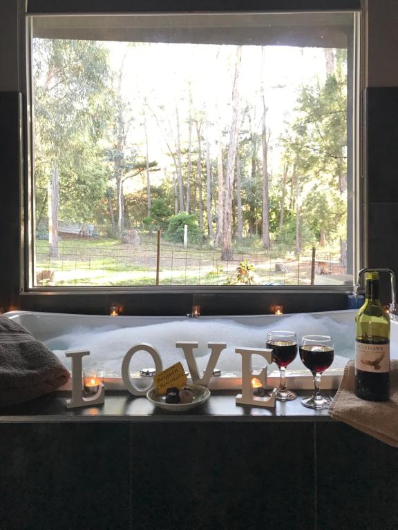 a table with two glasses of wine and a window at Spa Suites at RAVEN in Hepburn Springs