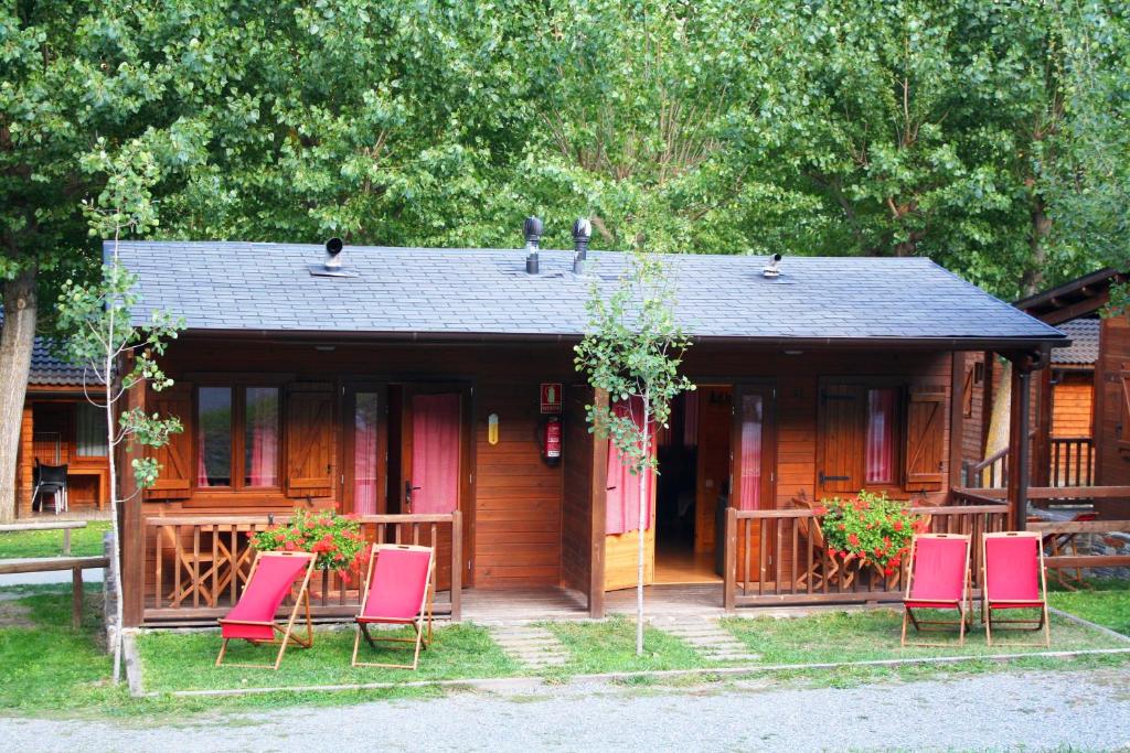 una cabaña con sillas rosas frente a ella en Bungalows Nou Camping, en Guingueta