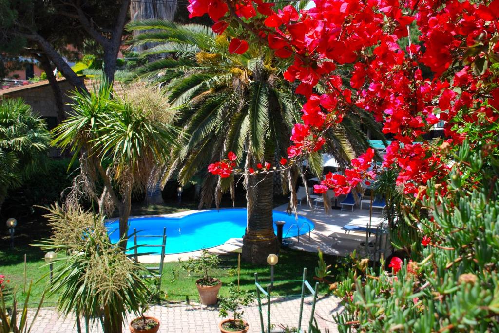 un jardín con flores rojas y una piscina en Residence dei Fiori, en Campo nell'Elba