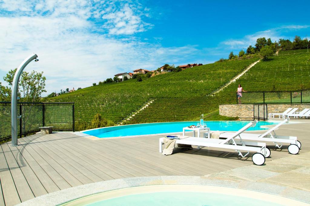 a swimming pool with two lounge chairs next to a hill at Réva Resort in Monforte dʼAlba