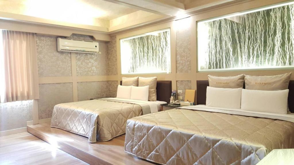 two beds in a room with two windows at Wind Coast Motel in Hsinchu City
