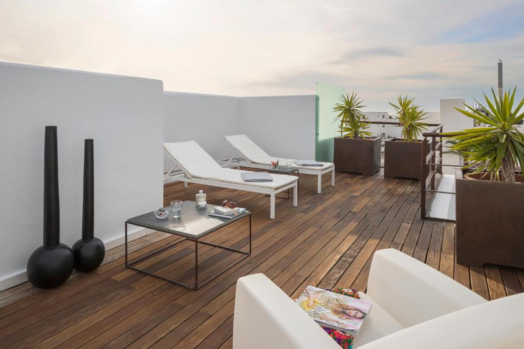 a balcony with white chairs and a table at Hotel Boutique Ses Pitreras in San Antonio Bay