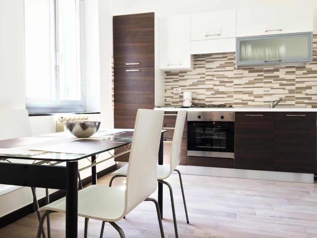 eine Küche mit einem Esstisch und weißen Stühlen in der Unterkunft Miramare Apartment Genova in Genua