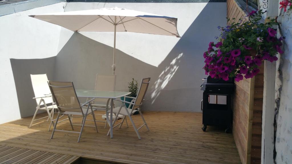 un patio avec une table, des chaises et un parasol dans l'établissement La Caloge, à Fécamp