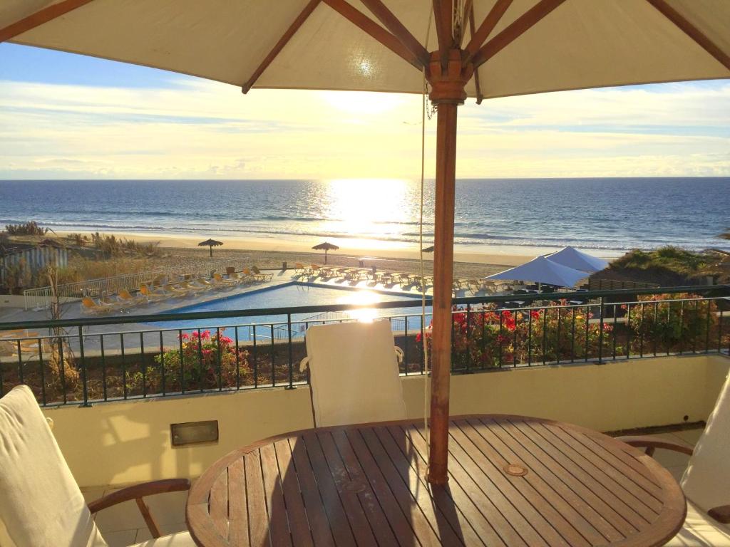 a table with an umbrella on a balcony overlooking the beach at Paradise Beach in Porto Santo
