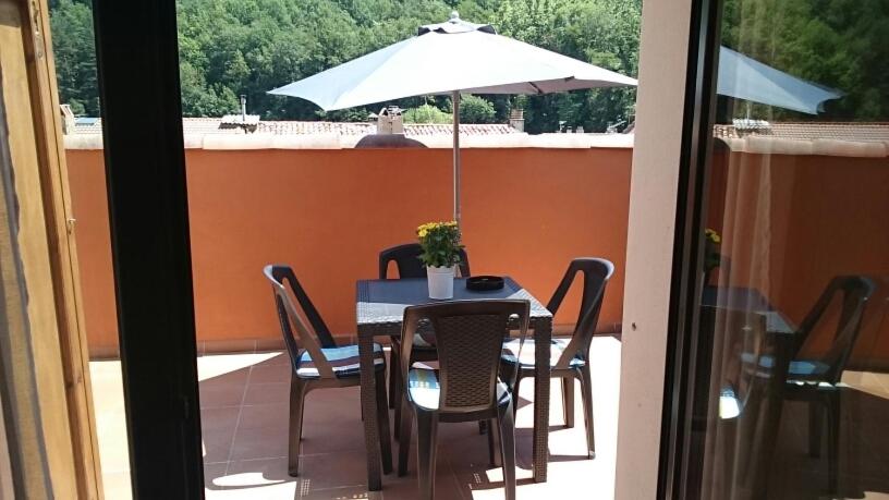 リベス・デ・フレセルにあるAtico en centro Ribes de Freserのテーブルと椅子、バルコニー(パラソル付)