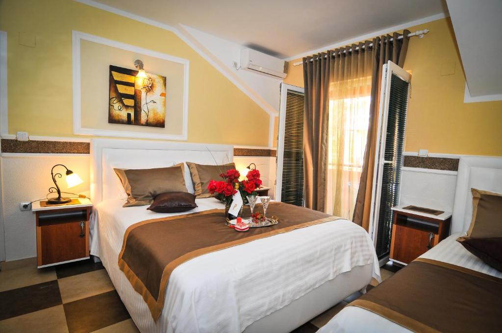 um quarto com duas camas e flores sobre uma mesa em Apartments Scepanovic em Tivat