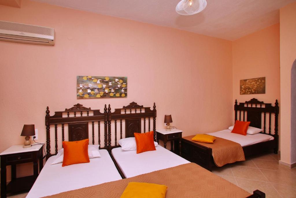 a bedroom with two beds with orange and white pillows at Maria Studios in Neo Klima