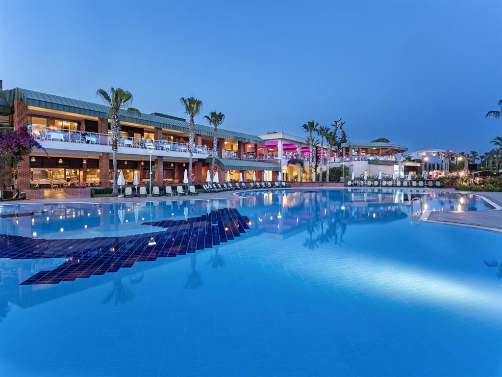 a large swimming pool at a resort at night at Pine Beach Belek in Belek