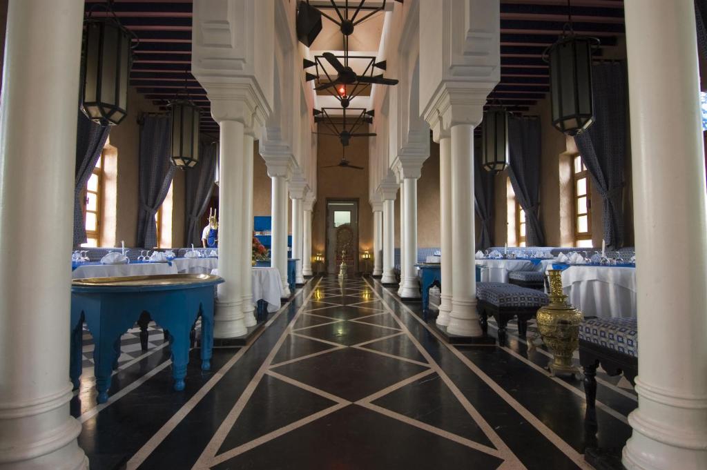 un couloir avec des tables et des chaises bleues dans un bâtiment dans l'établissement El Pueblo Tamlelt, à Agadir